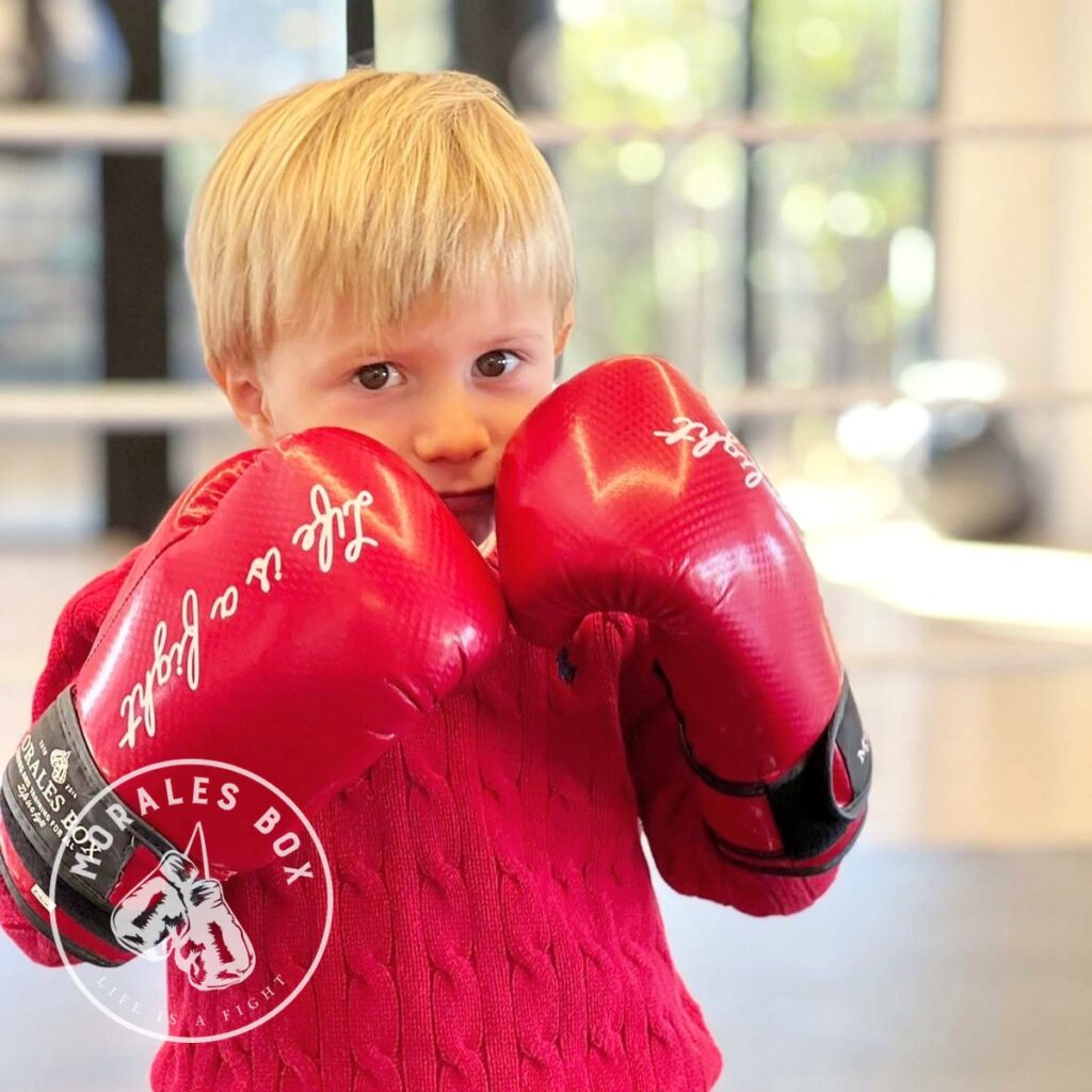 Niño con guantes de boxeo rojos de Morales Box en guardia