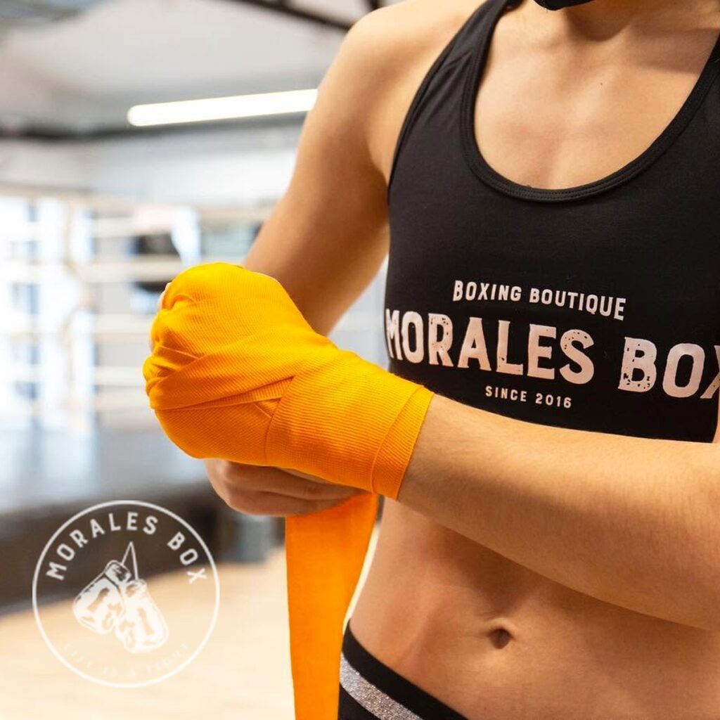 Manos con vendas naranjas de boxeo en el gimnasio Morales Box